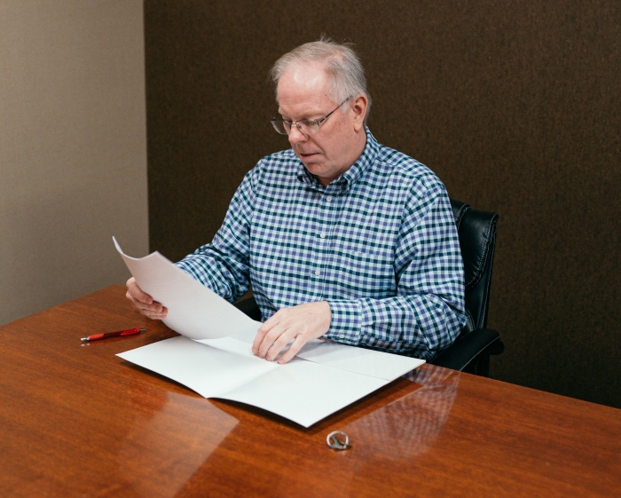 A man in a plaid shirt reviewing legal documents regarding an entitled neighbor legal dispute. A man in a plaid shirt reviewing legal documents regarding an entitled neighbor legal dispute.