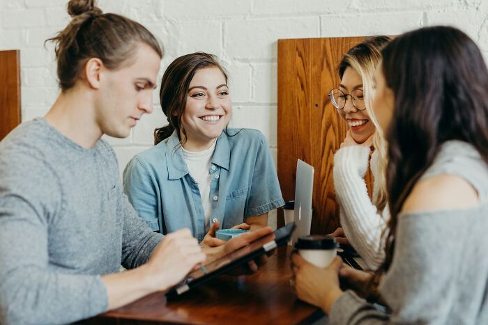 A group of friends laughing and talking in a cafe, showcasing a genuine social gathering contrasted with Hollywood.