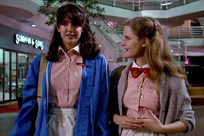 Two young women wearing striped uniforms in a mall, evoking nostalgic photos from 80s kids childhoods.