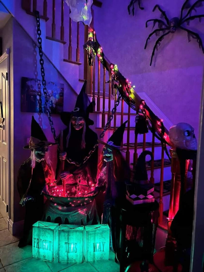 Spooky witch figures around a bubbling cauldron with purple lighting for Halloween indoor decor.