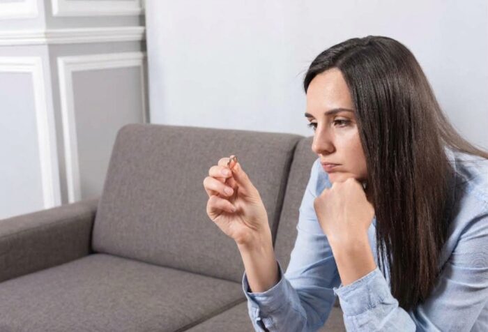 A sad woman holding a wedding ring as she decides she cannot marry her fiancé. A sad woman holding a wedding ring as she decides she cannot marry her fiancé.