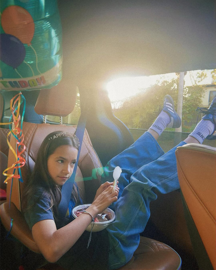 Fiona, daughter of Chad Lowe's friend, wearing a tiara and sitting in a car with birthday balloons.