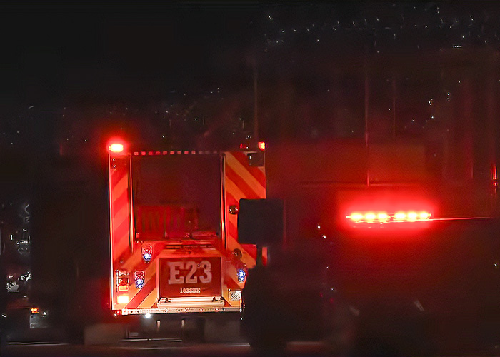 Rear view of an emergency fire truck with its red warning lights flashing at night.