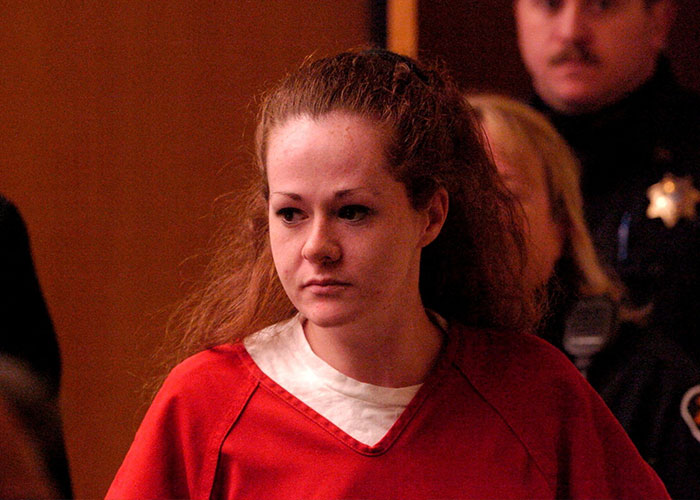 Christa Pike standing in a courtroom wearing a red inmate uniform