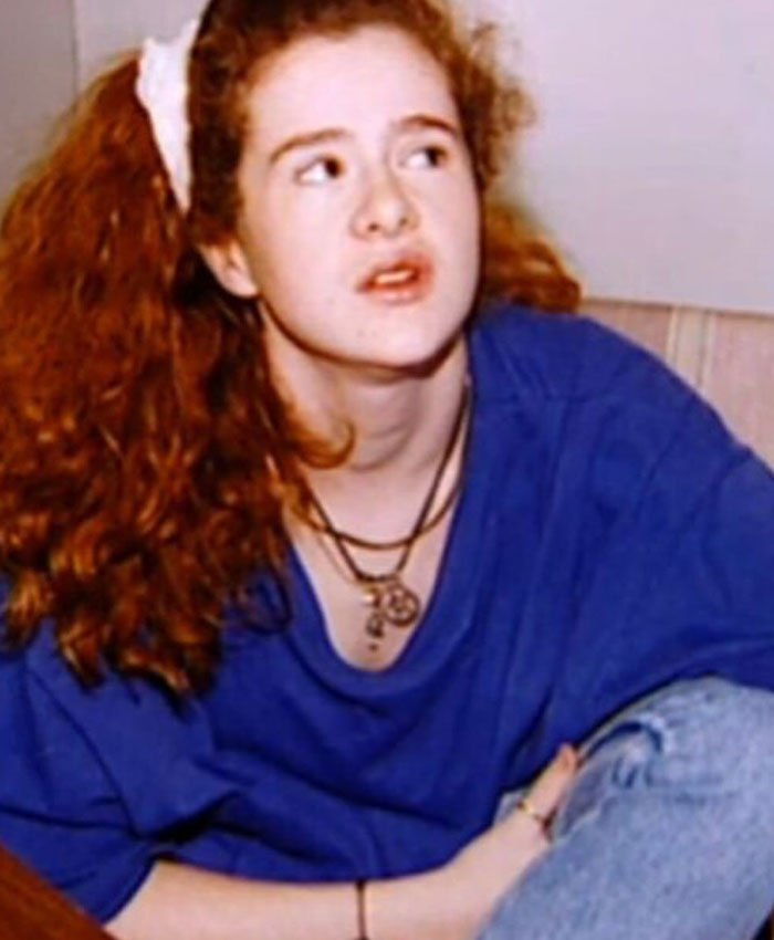 A young Christa Pike with long curly hair wearing a blue shirt