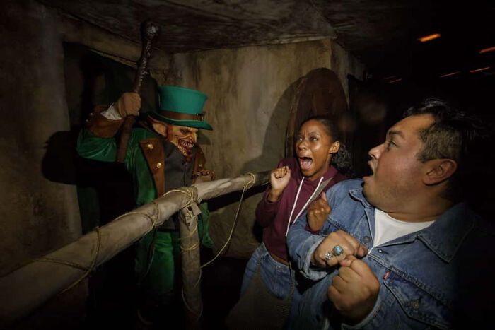 A couple recoils in fear from an evil leprechaun in a haunted house attraction.