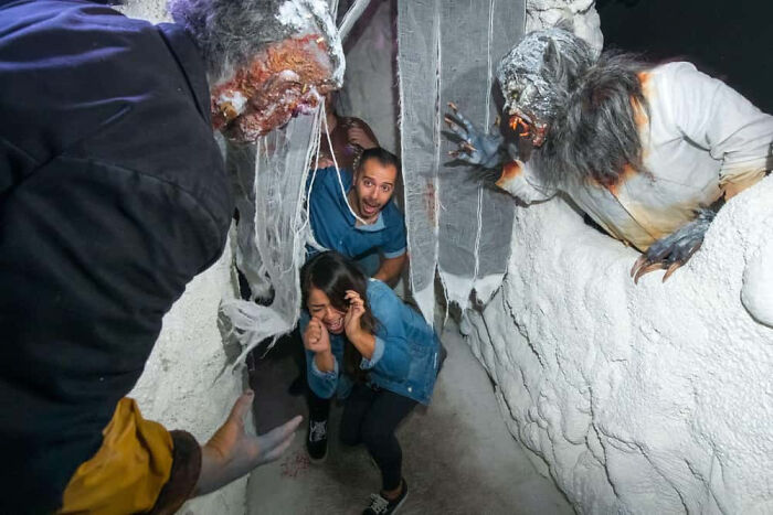 Panicked visitors cornered by monsters in a haunted house photo.