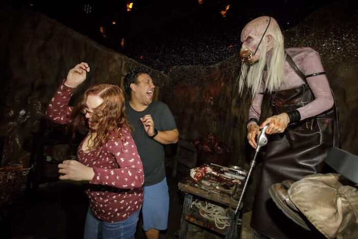 Fearful couple cowering near an eerie character in a haunted house photo.