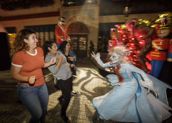 Scared visitors reacting to a monster performer in a haunted house photo.
