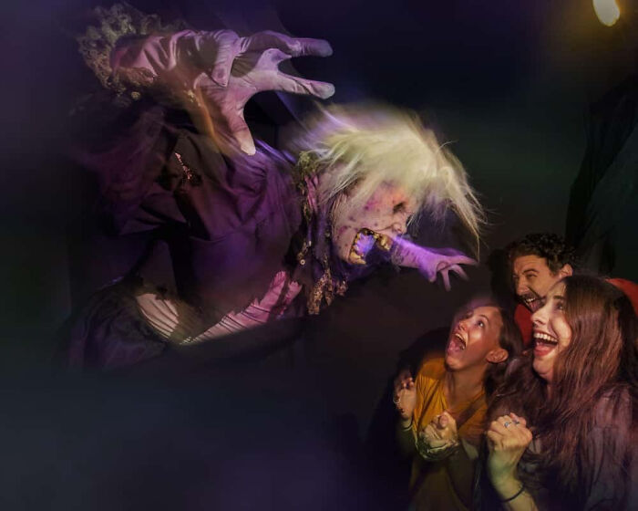 Terrified visitors reacting to a scary monster reaching for them in a haunted house