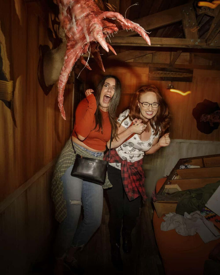 Two women screaming in fear during a scary moment inside a haunted house