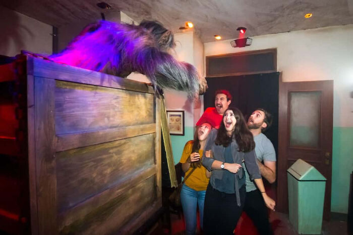 Terrified visitors screaming at a creature display in a haunted house.