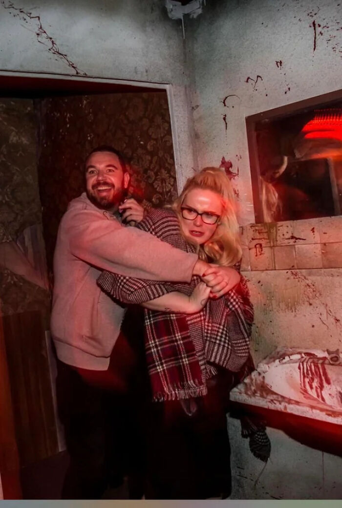 Frightened couple holding each other tightly inside a scary haunted house.