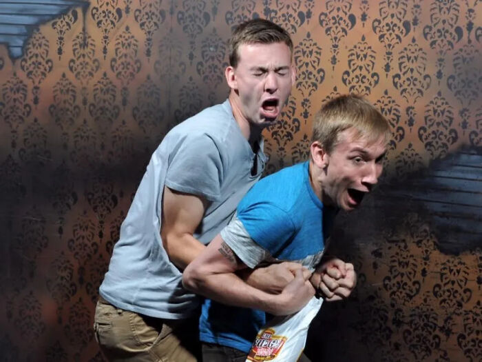 Two men terrified in a haunted house photo clutching each other