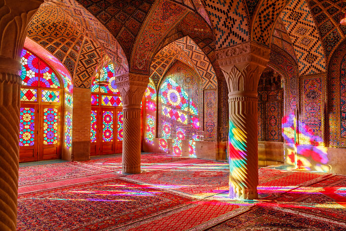 Vibrant stained glass windows casting colorful light patterns in a mosque showcasing the beauty of spaces