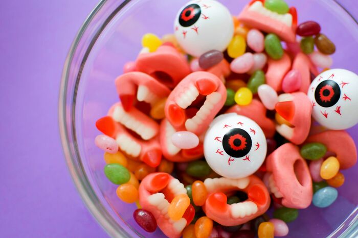 A glass bowl filled with scary gummy teeth and eyeballs, representing Halloween conflicts over spooky party snacks.