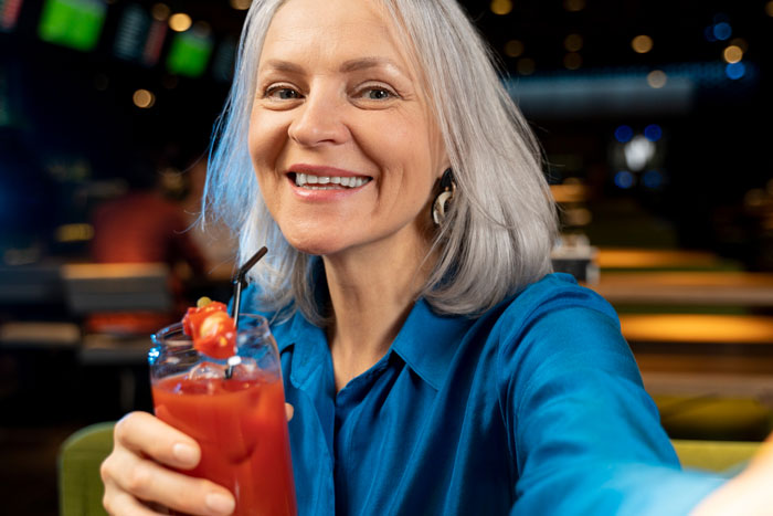 Older woman smiling with a cocktail representing toxic mom Older woman smiling with a cocktail representing toxic mom