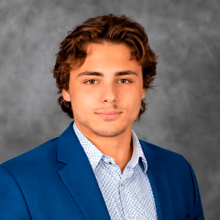 Headshot of the Cornell 7 frat bro in a blue suit jacket