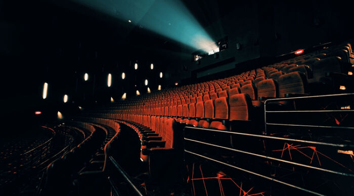Empty movie theater with red seats and a projector light, perfect for movie fans Empty movie theater with red seats and a projector light, perfect for movie fans