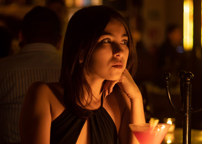A pensive woman sitting at a dimly lit restaurant bar with a cocktail, regretting her decision to trick her BF. A pensive woman sitting at a dimly lit restaurant bar with a cocktail, regretting her decision to trick her BF.