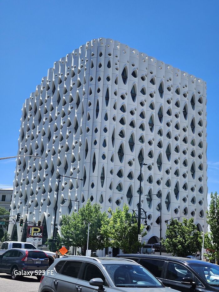White building with intricate perforated facade and organic window patterns