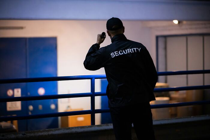 A security guard using a flashlight in a dark building, illustrating spooky things people experienced.