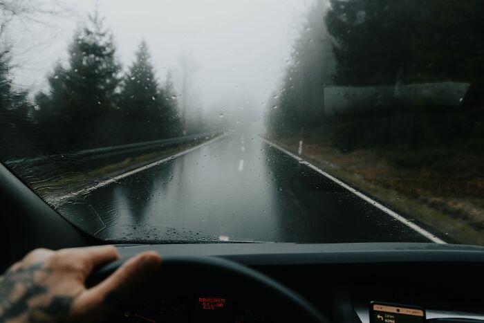 Driver view through a rain-covered windshield on a foggy forest road, showing spooky things people experienced