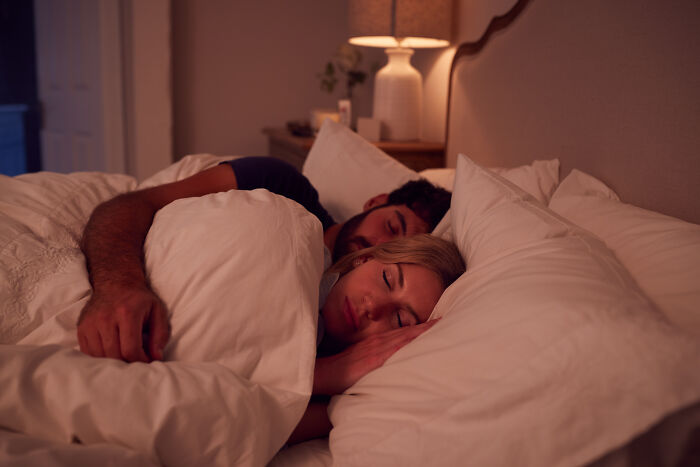 A couple sleeping comfortably together in bed at night, capturing spooky things people experienced while resting