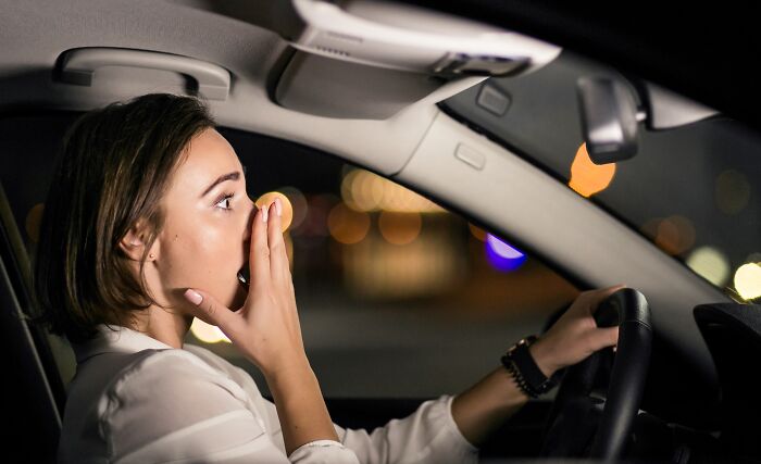A shocked woman driving a car at night, representing spooky things experienced in real life.