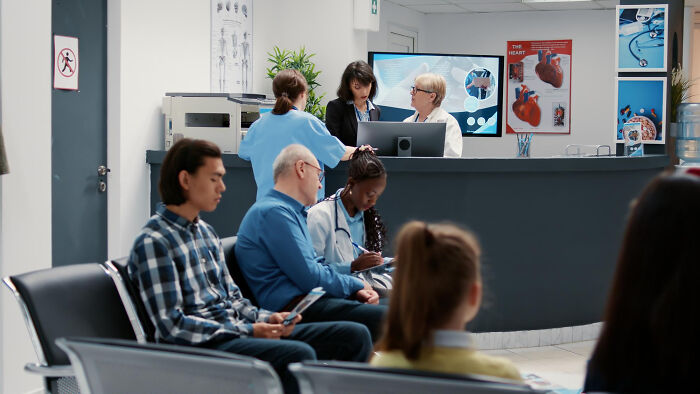 Waiting room with diverse people and medical staff at clinic reception