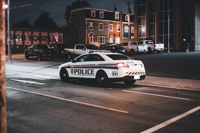 Police car parked at night on urban street with buildings