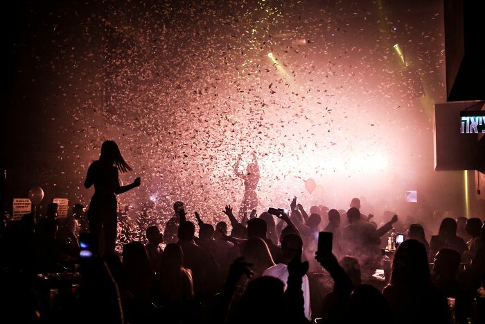 Crowd enjoying a party with confetti and vibrant lighting effects