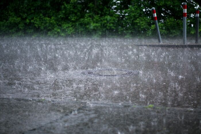 Heavy rainwater flooding a street with splashes and wet pavement