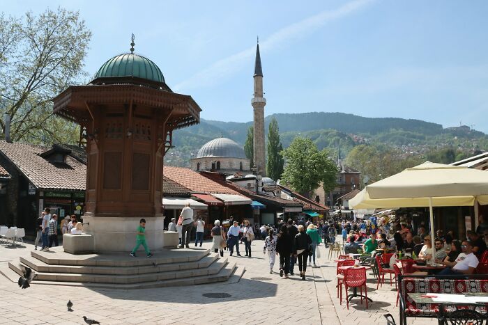 Birds eye market square with mosque minaret and crowd under blue sky