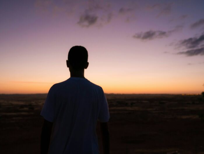 Silhouette of a person looking at an eerie sunset sky