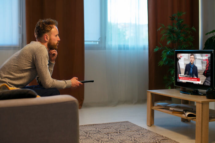 Man intently watching news on television in dimly lit living room