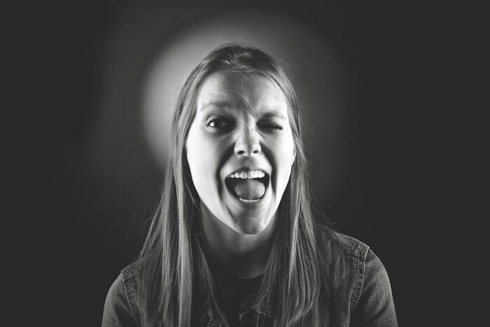 A woman winking and screaming in black and white, depicting weird things people encounter.