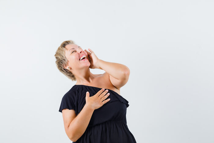 A woman in a black dress laughing heartily, contrasting the creepy and scary vibes of working during the night.