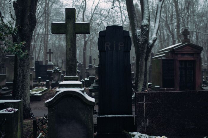 A quiet, creepy graveyard covered in snow during the night