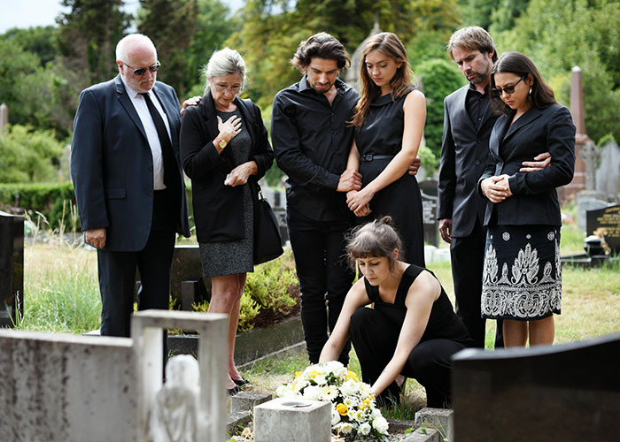 A family dressed in black at a grave site mourning their late bro during a funeral service. A family dressed in black at a grave site mourning their late bro during a funeral service.