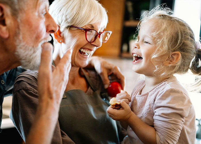 Grandparents playing and laughing joyfully with their young granddaughter at home, showing strong family bonds. Grandparents playing and laughing joyfully with their young granddaughter at home, showing strong family bonds.