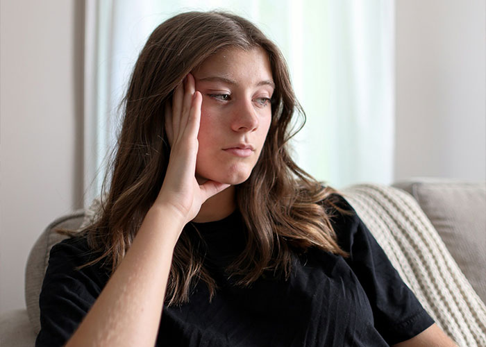 A thoughtful young woman sitting on a couch resting her hand on her head, illustrating how women betray SIL. A thoughtful young woman sitting on a couch resting her hand on her head, illustrating how women betray SIL.