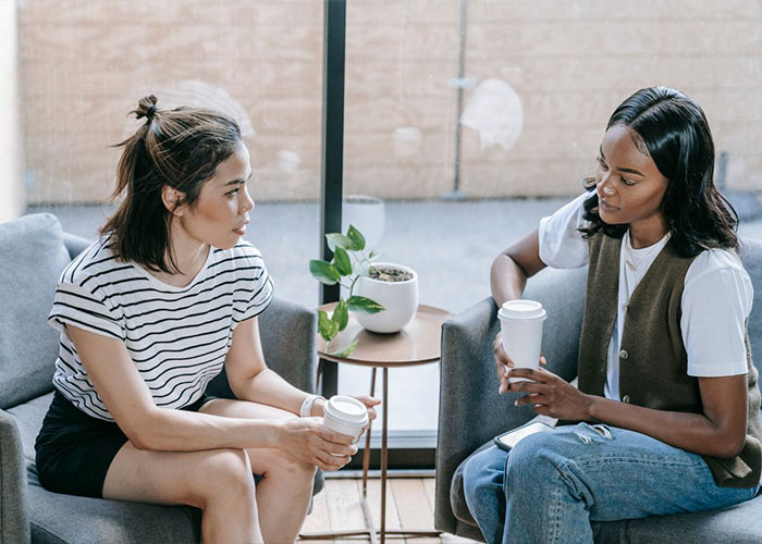 Two women having coffee representing sisters-in-law talking about family drama. Two women having coffee representing sisters-in-law talking about family drama.