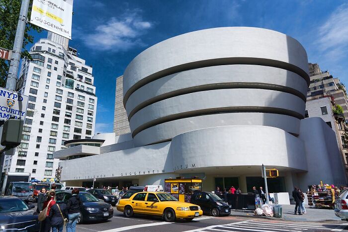 Curved white Guggenheim Museum building with horizontal bands on busy city street