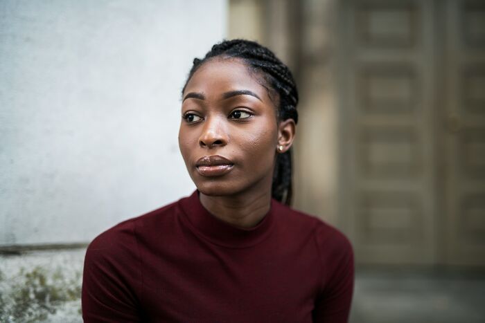 A thoughtful young woman sitting outdoors during a tense situation involving Halloween conflicts.