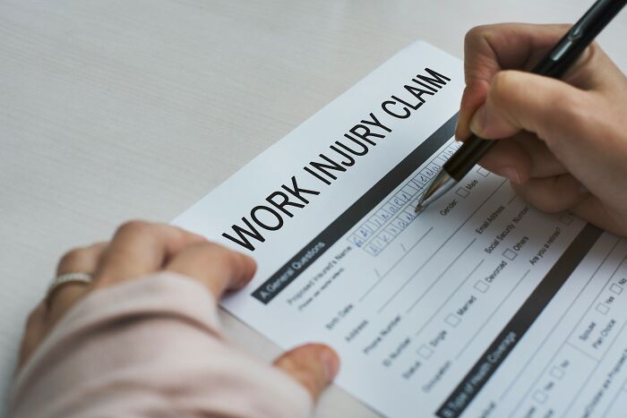 A person filing out a work injury claim form, revealing behind the scenes details at companies people trust.