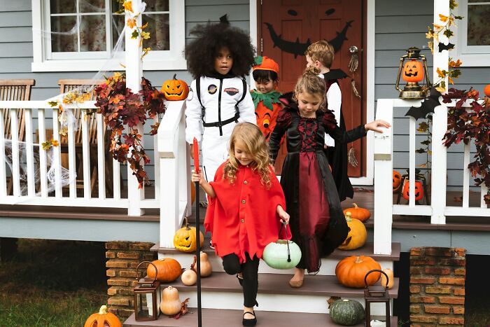 Children in spooky costumes walking down porch steps, depicting Halloween conflicts and trick-or-treating fun.