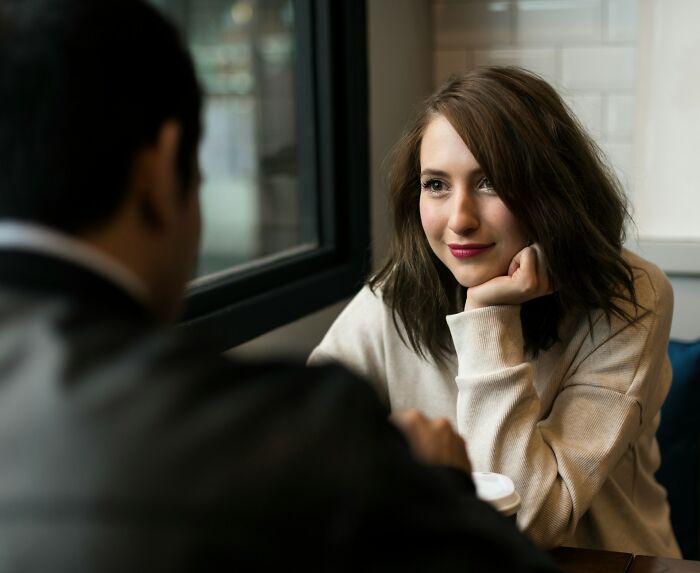 A couple sitting together at a table engaged in conversation about relationships and infidelity stories.