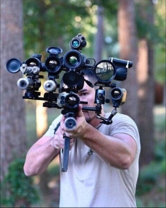 Man aiming a gun outfitted with multiple camera lenses in outdoor setting