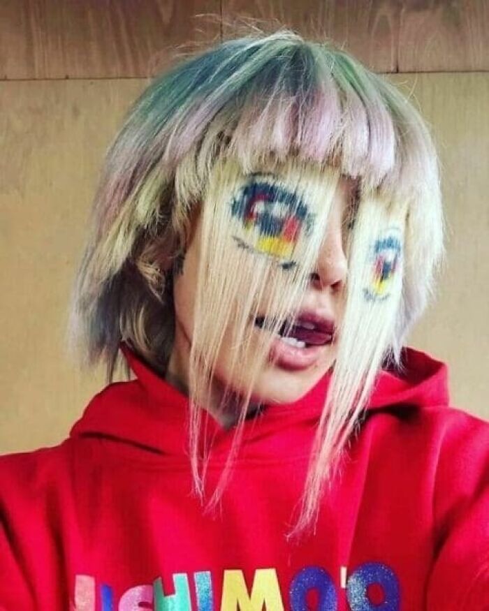 Person with hair styled and painted to look like cartoon eyes on their face